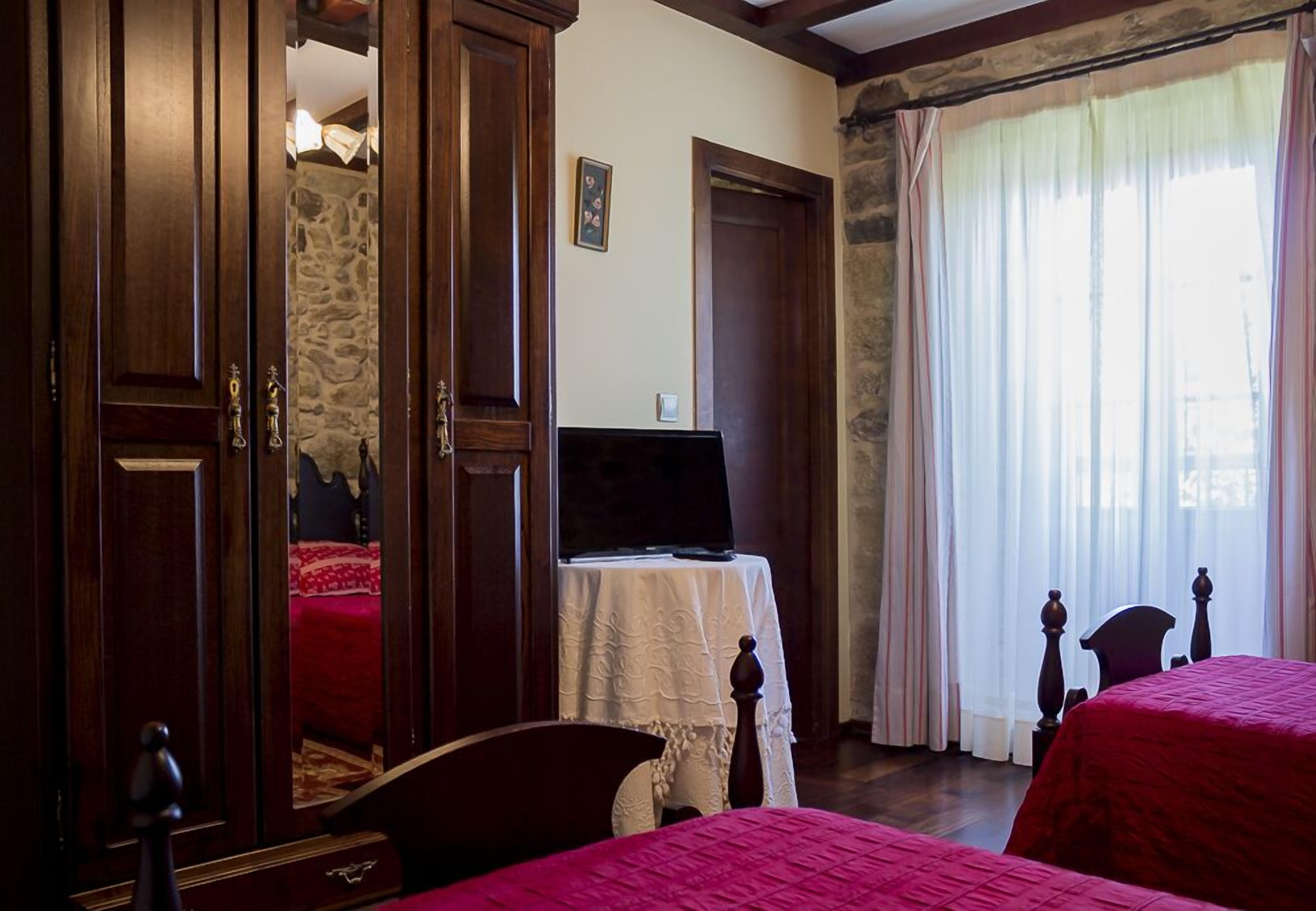 A bedroom with a bed, a TV on a table, and a wardrobe.