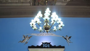 A lobby with a blue wall, a chandelier, a fireplace, and a sign reading "ROMA HOUSE". - The Roma House (Rome)