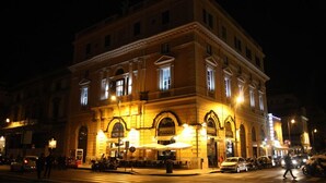 A historic building with arched windows and a central entrance, illuminated at night. - The Roma House (Rome)