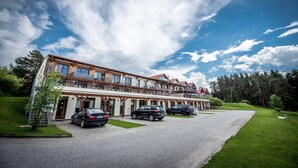 Un hotel grande con varios pisos, un espacio al aire libre cubierto y varios autos estacionados.