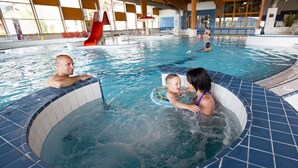 Una piscina interior con zona de hidromasaje, tobogán y sección de natación separada.