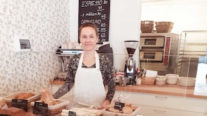 Un mostrador de panadería con varios productos horneados a la vista, un menú en una pizarra y un letrero que dice "Chievo Se Soli".
