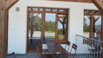 Enjoy al fresco dining in this charming outdoor space with a wooden table and chairs under a covered pergola.