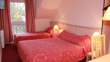 Een hotelkamer met twee bedden, een balkon en uitzicht op bomen.