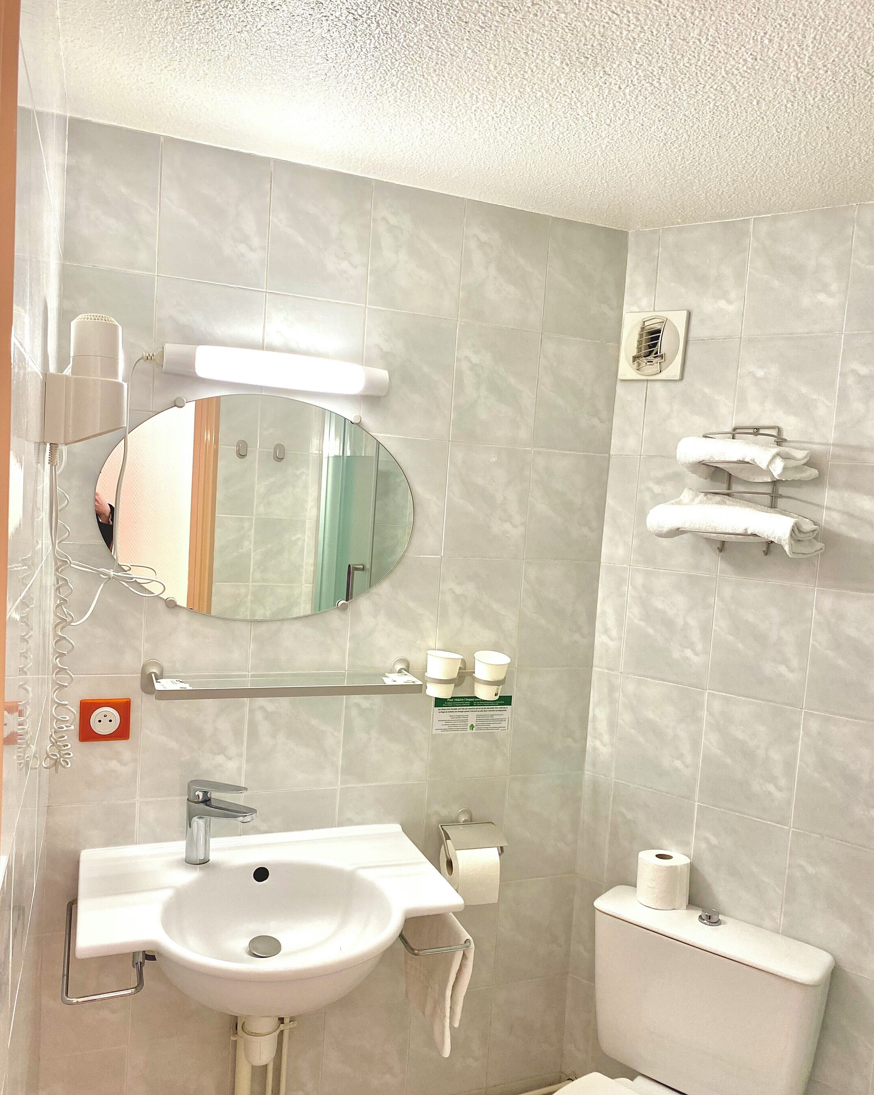A bathroom with a sink, mirror, towel rack, and toilet.