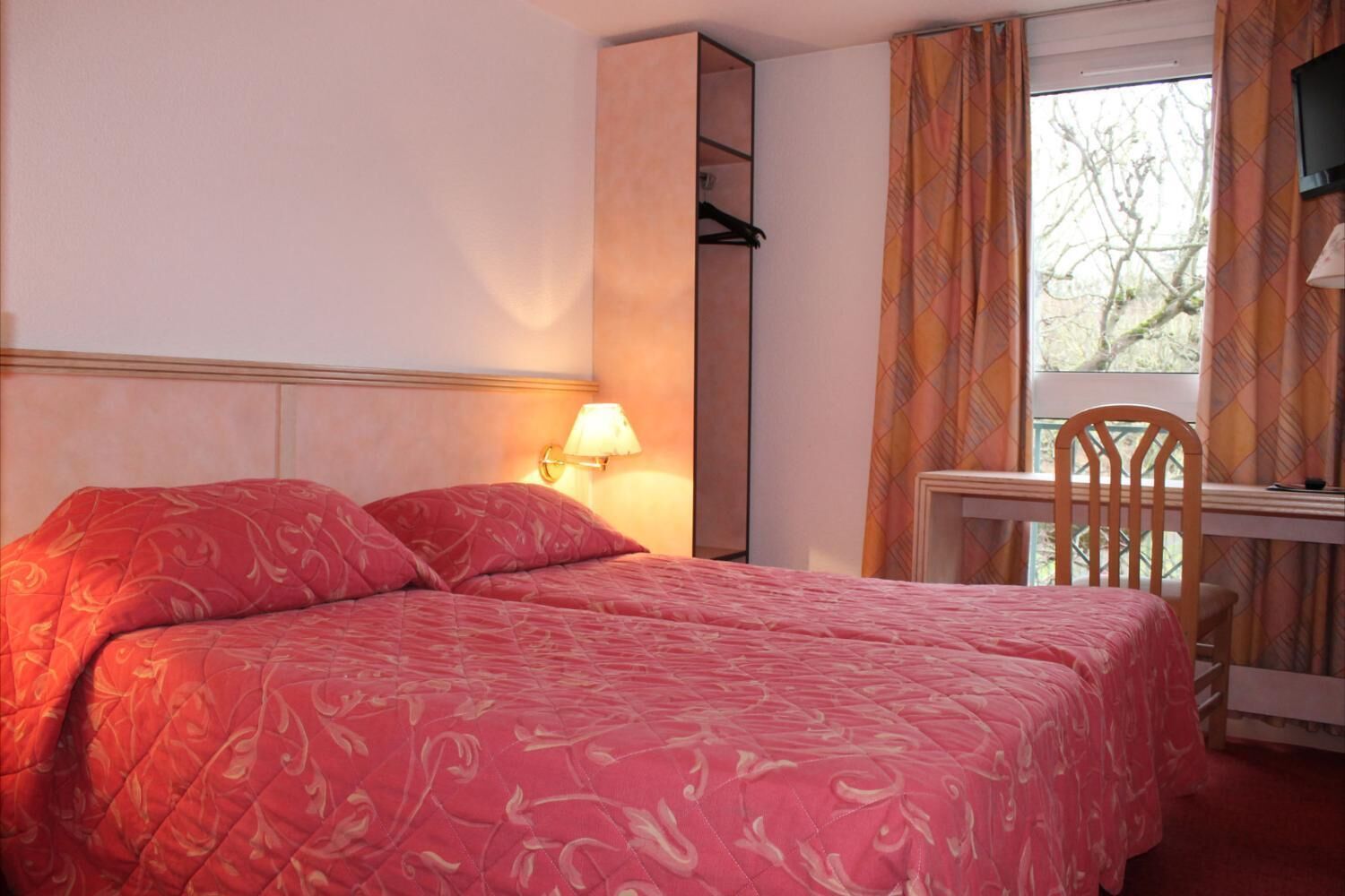 A hotel room with a bed, a desk, and a chair.