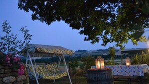 An outdoor seating area with a table and chairs, a stone wall, and a backdrop of hills. - Agriturismo Le Spighe (Proceno)