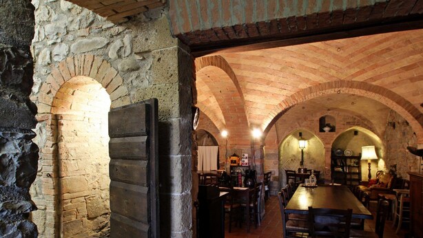 A rustic stone-walled room with a long wooden table and chairs, arched brick ceilings, and a stone fireplace. - Agriturismo Le Spighe (Proceno)