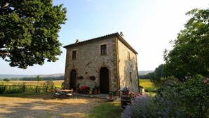 A stone building with two arched doorways, a small porch with seating, and a gravel path leading to it. - Agriturismo Le Spighe (Proceno)
