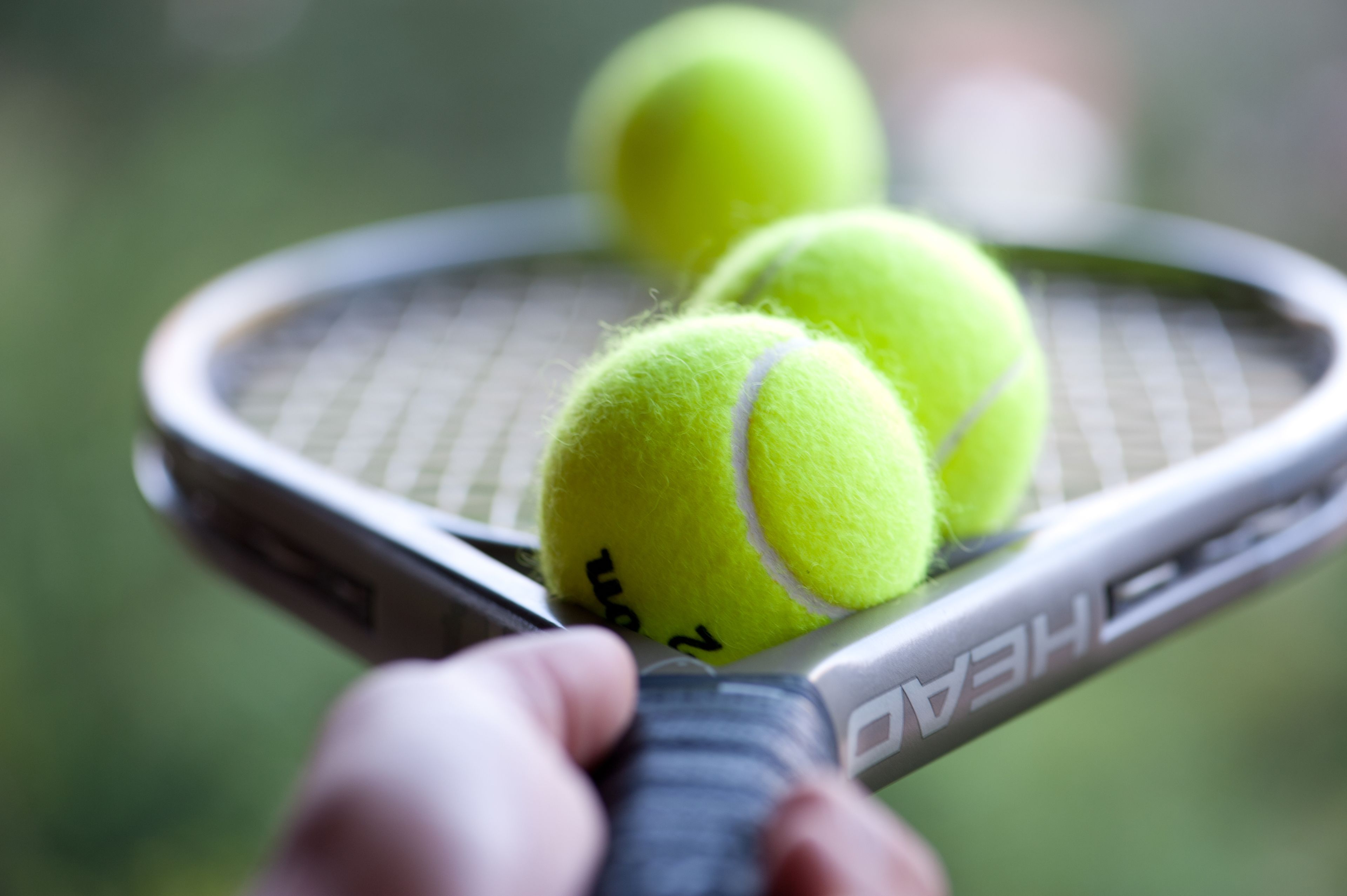 Une raquette de tennis avec deux balles de tennis.