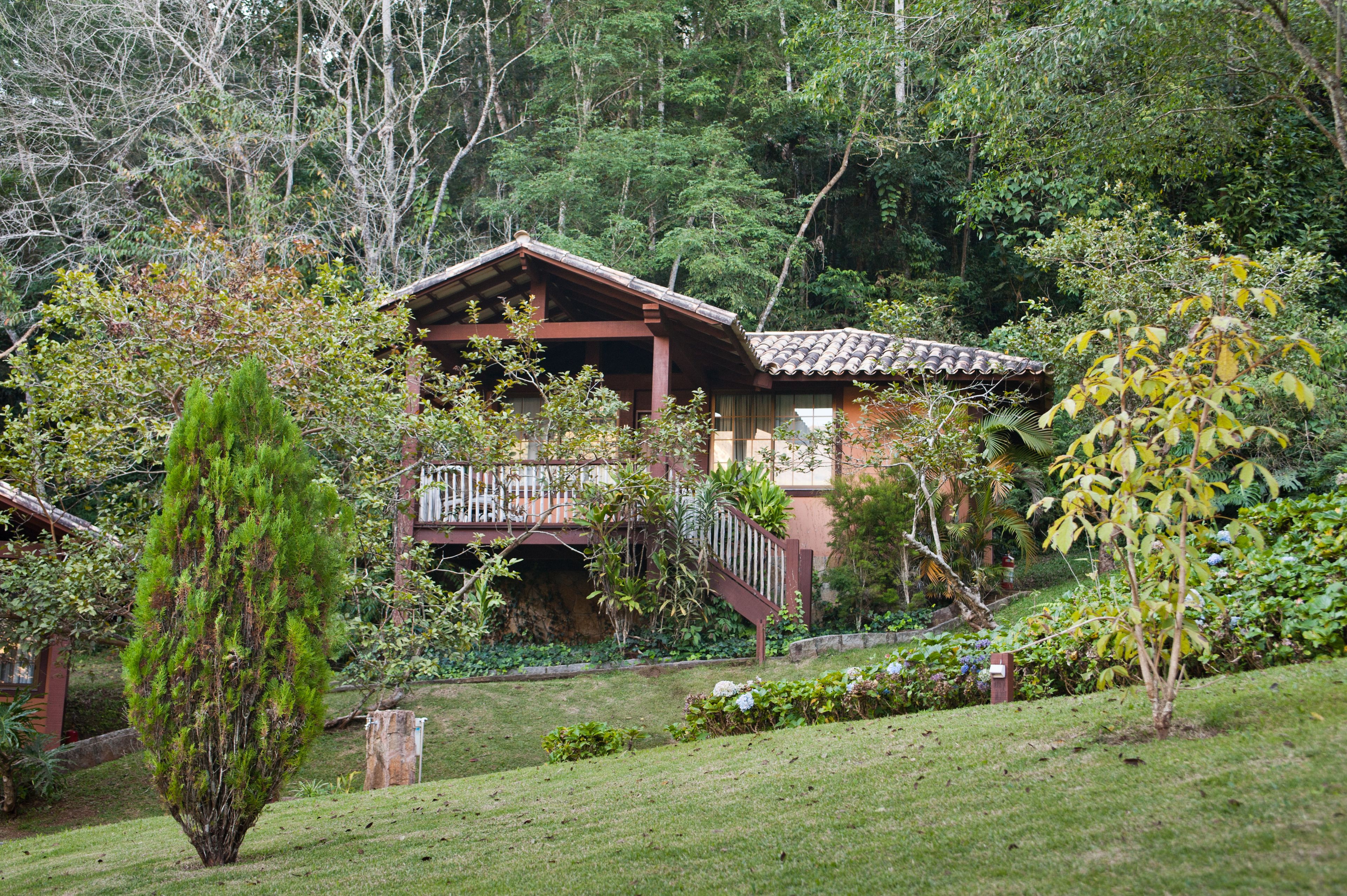 Una casa de madera tradicional con balcón, rodeada de exuberante vegetación y árboles.