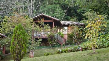 Una casa de madera tradicional con balcón, rodeada de exuberante vegetación y árboles.