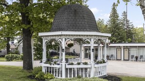 A gazebo with a dome roof, surrounded by a white fence and plants. - Catalina Motel (Sault Ste. Marie)