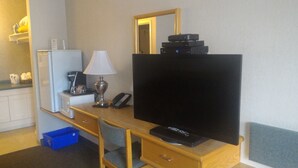 A hotel room with a wooden desk, a flat-screen TV, a lamp, a telephone, a coffee machine, and a refrigerator. - Catalina Motel (Sault Ste. Marie)