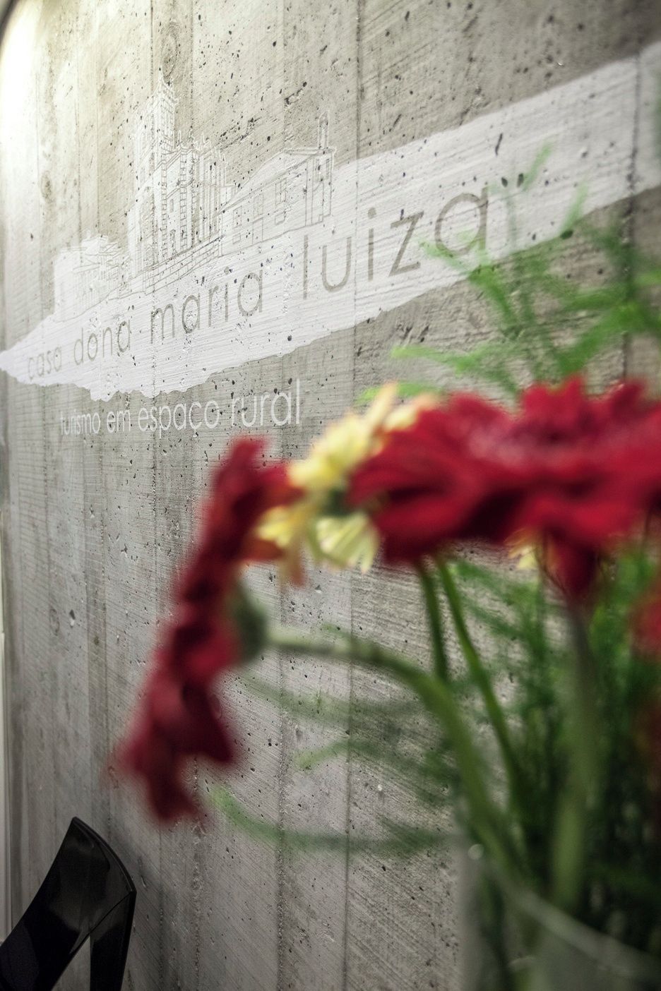 A wall with a partial view of a building's facade and a blurred foreground with a plant.