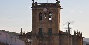 A historic tower with a clock, arched windows, and a bell. - Casa Dona Maria Luiza (Torre de Moncorvo)