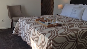 Ein Hotelzimmer mit einem Bett, einem Sessel, einer Ablage mit Snacks und einer Lampe.