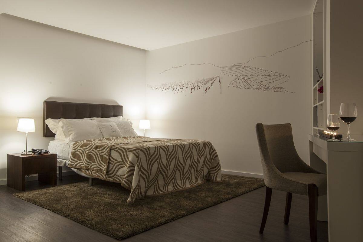 Ein Schlafzimmer mit einem Bett, Nachttischen, einem Sessel und einem Wandbild.