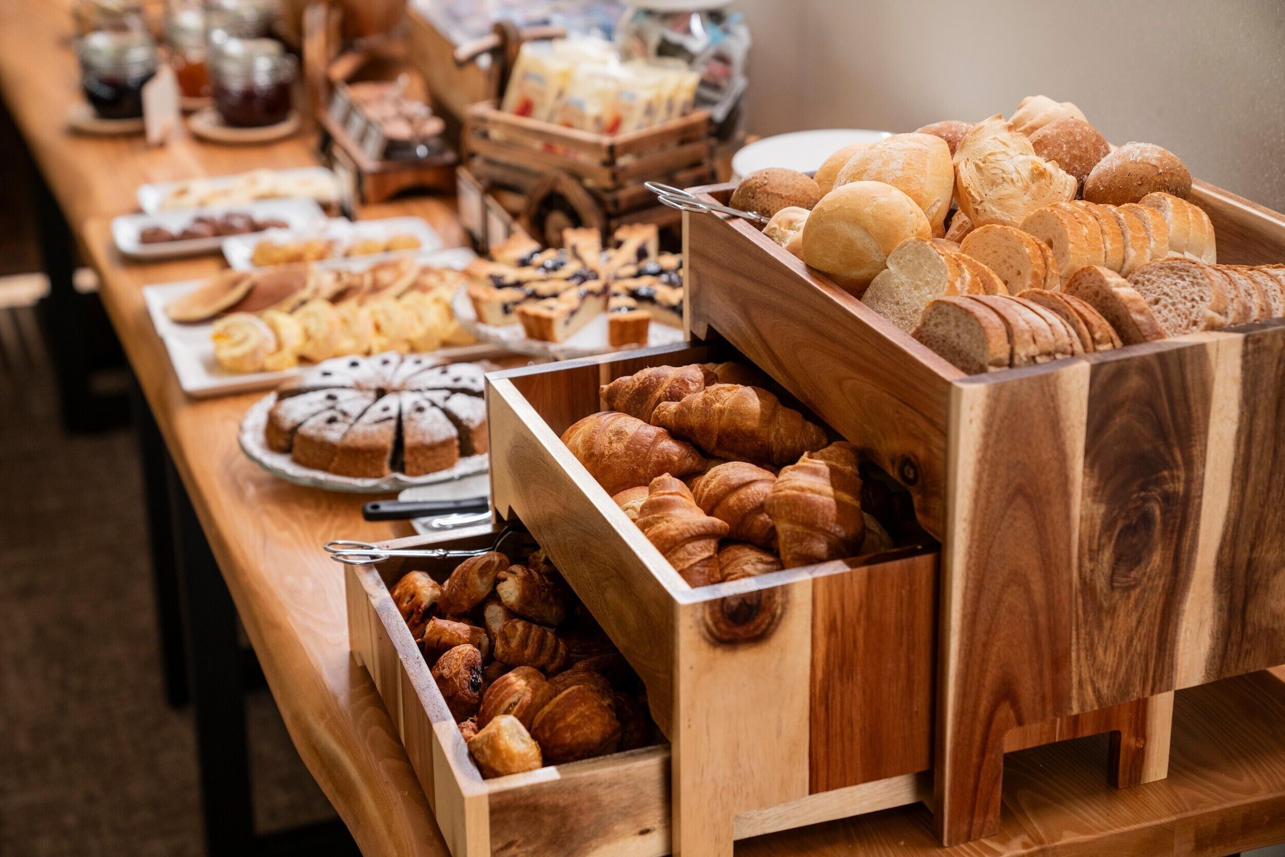 Una mesa de buffet con una variedad de productos horneados, como pan, pasteles y postres.