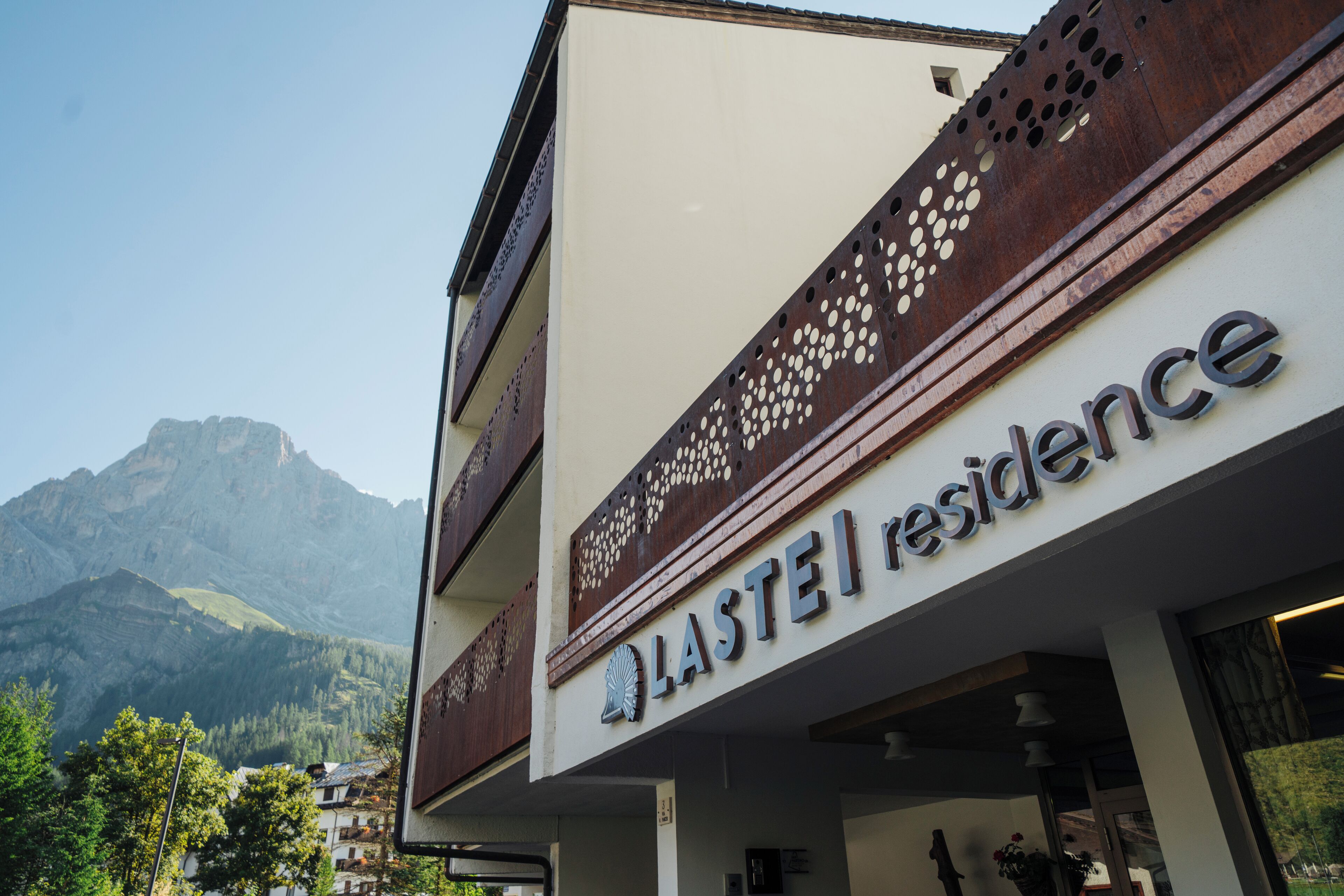 Un hotel llamado "LASTEI Residence" con un paisaje montañoso de fondo.