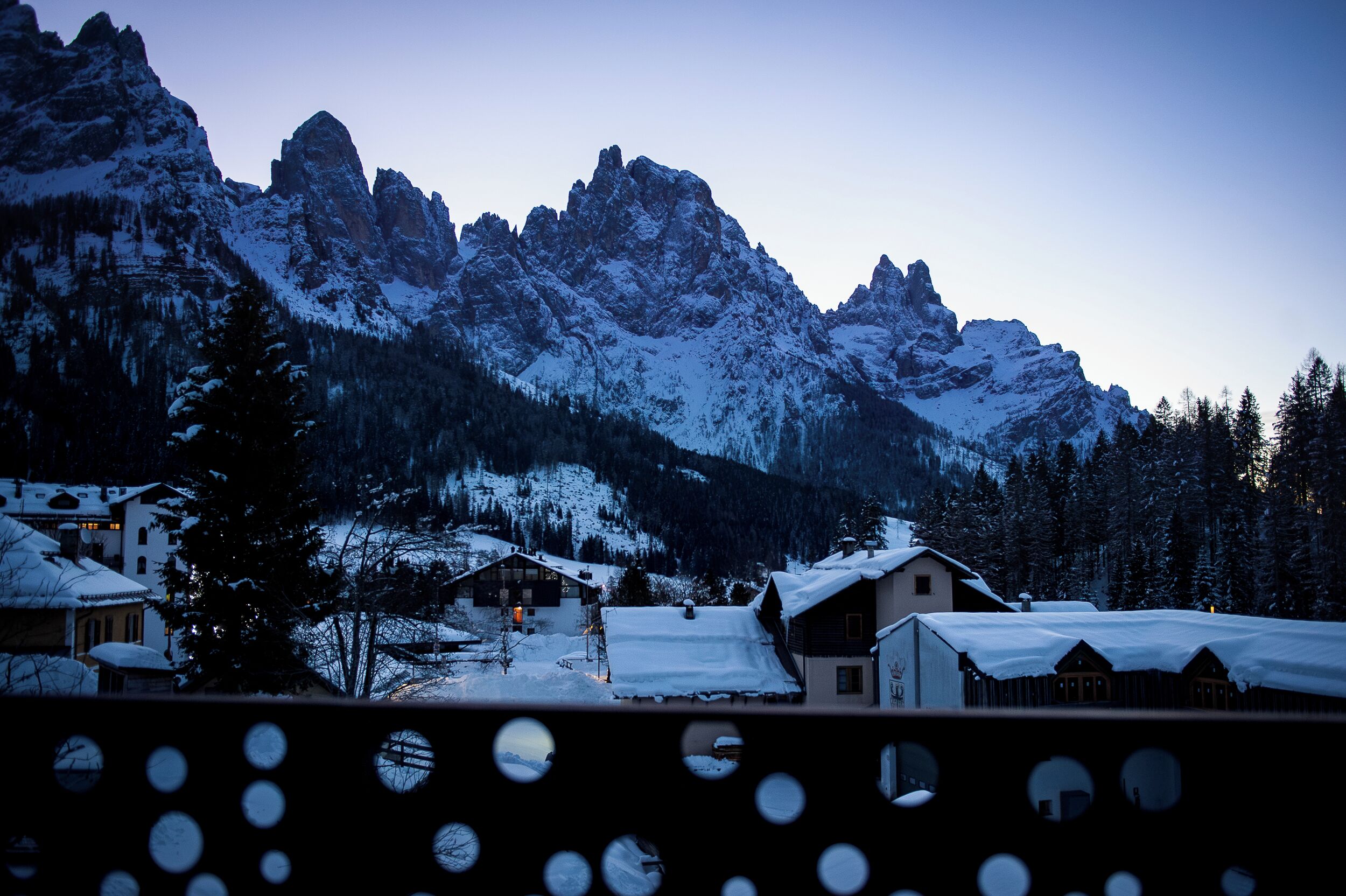 A mountain village with snow-covered houses and a prominent mountain range in the background.
