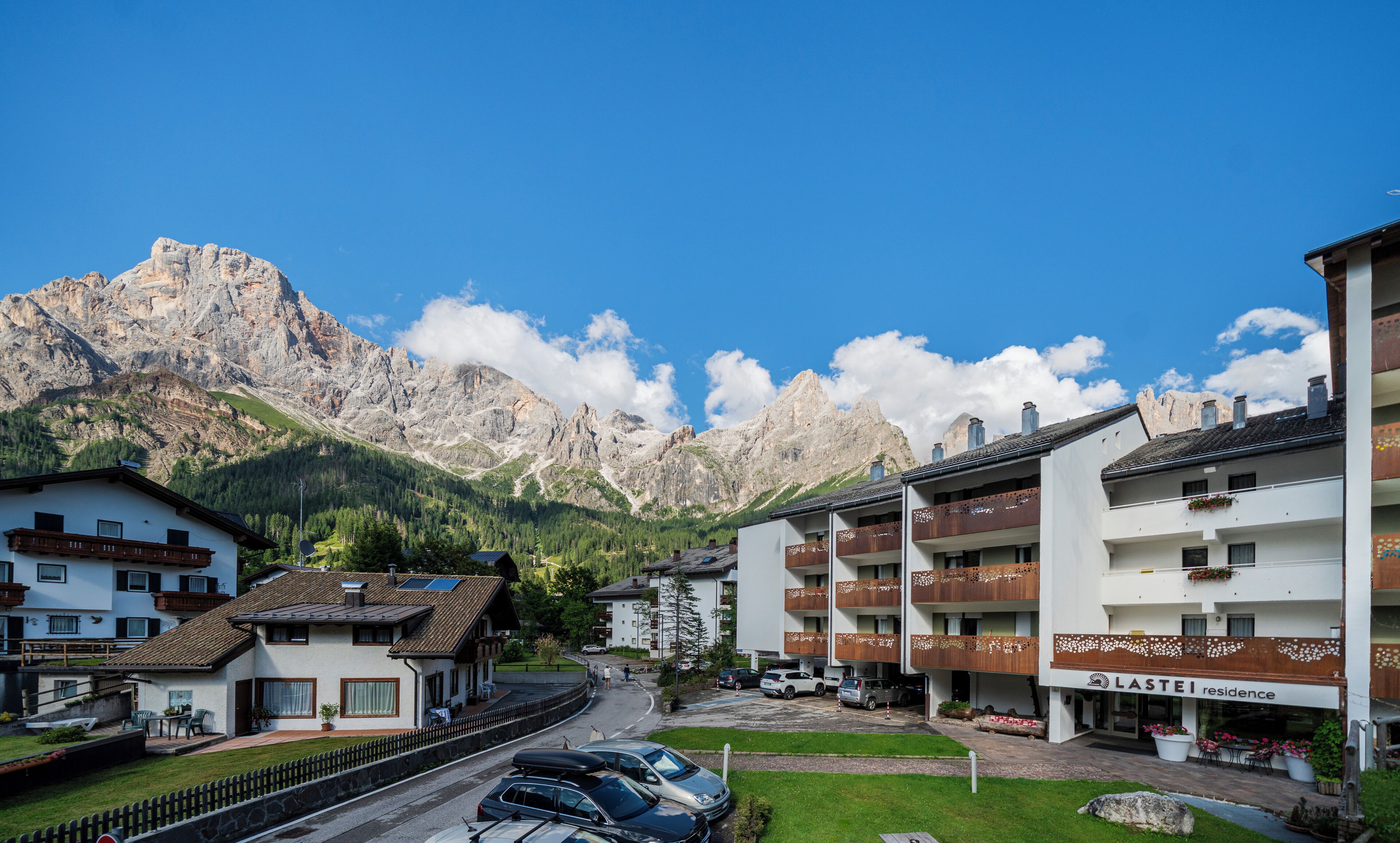A residential area with mountain views, a parking lot, and a building with a sign 'LASTEI residence'.