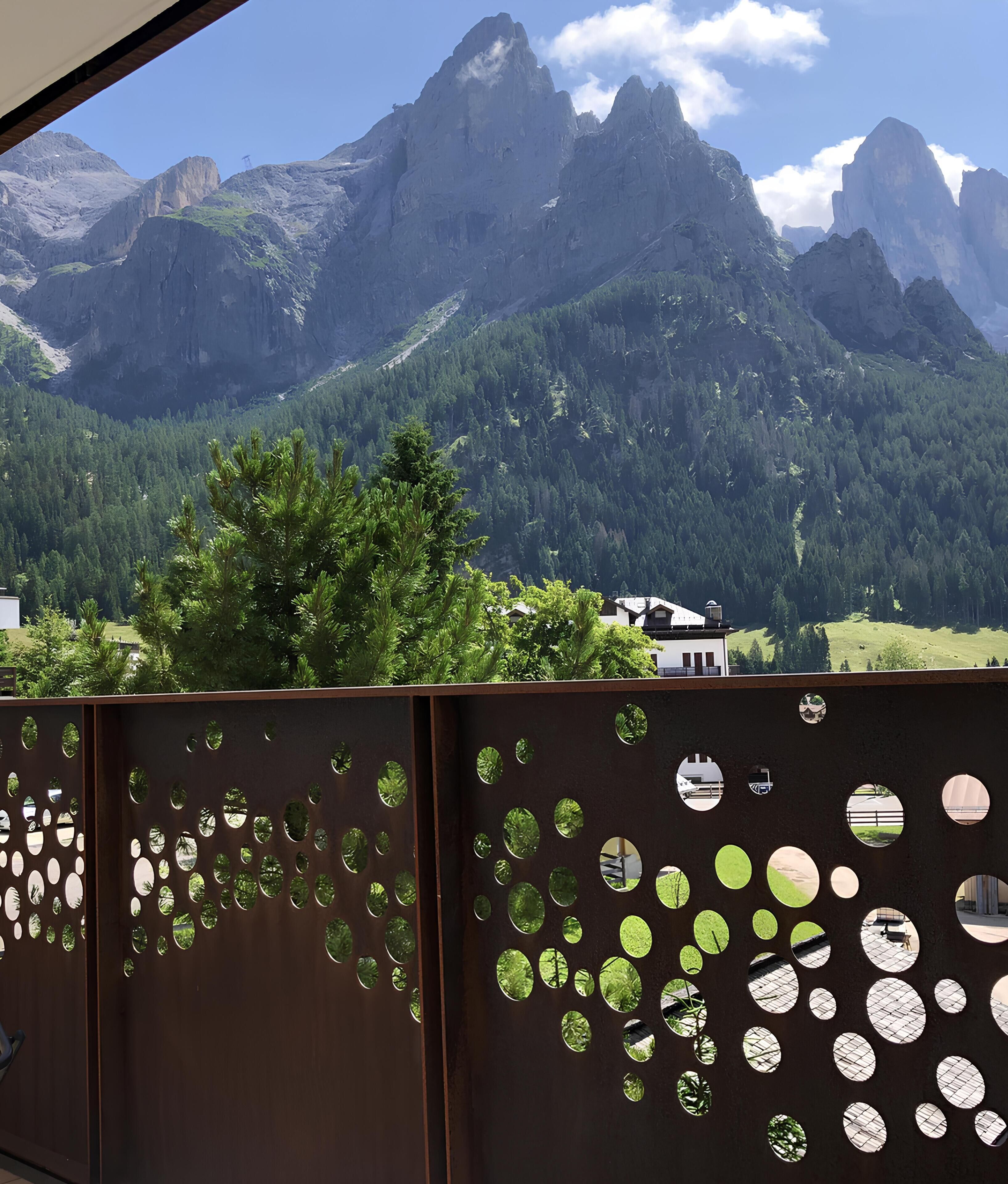 Eine Berglandschaft mit Blick auf ein Haus und einen Metallzaun mit runden Aussparungen.