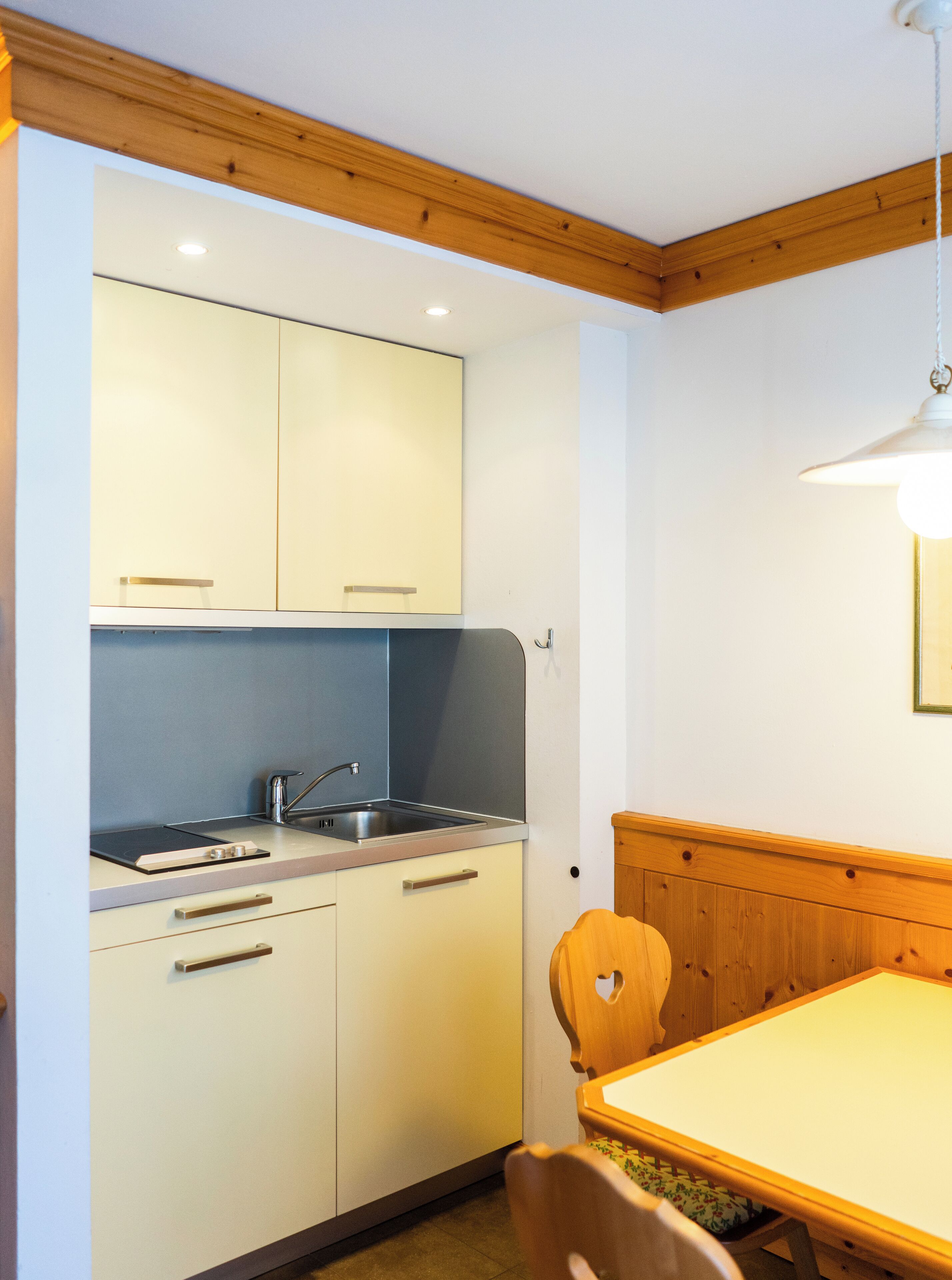 A compact kitchen with a sink, cabinets, and a dining area with a table and chairs.