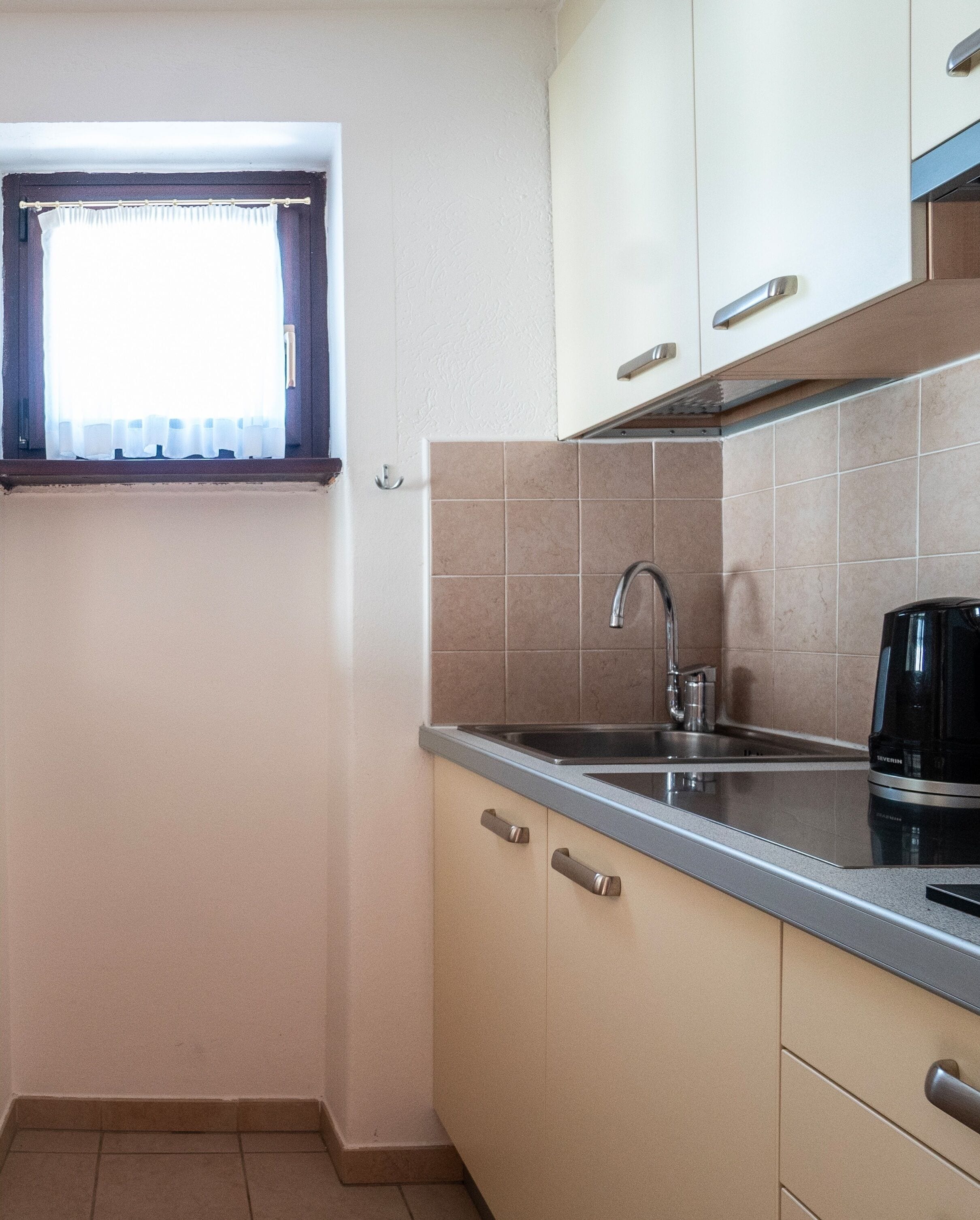 A compact kitchen with a window, a sink, and a coffee maker.