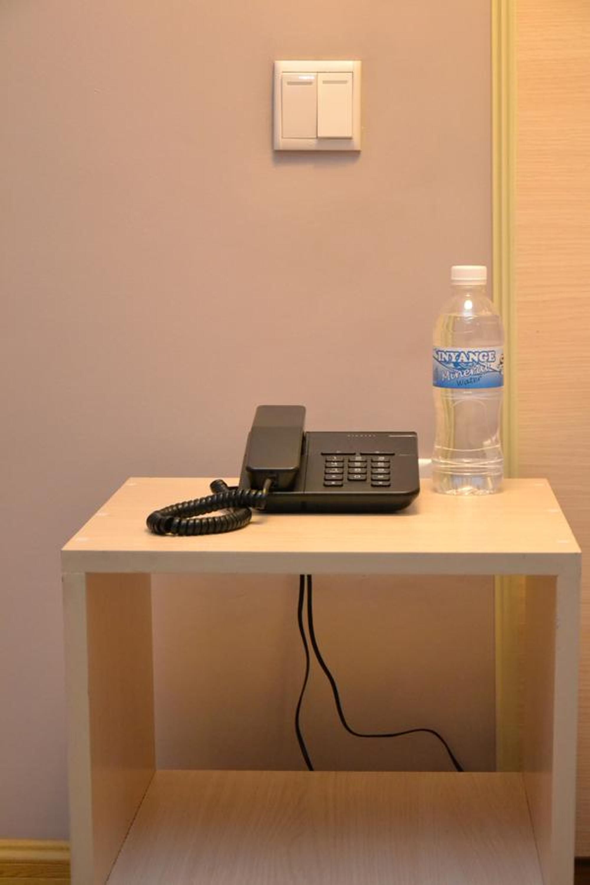 A small table with a telephone and a water bottle.