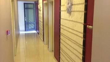 Un pasillo de hotel con suelo de baldosas, puertas y una pared con textura.