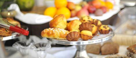 A buffet with various baked goods, fruits, and nuts.