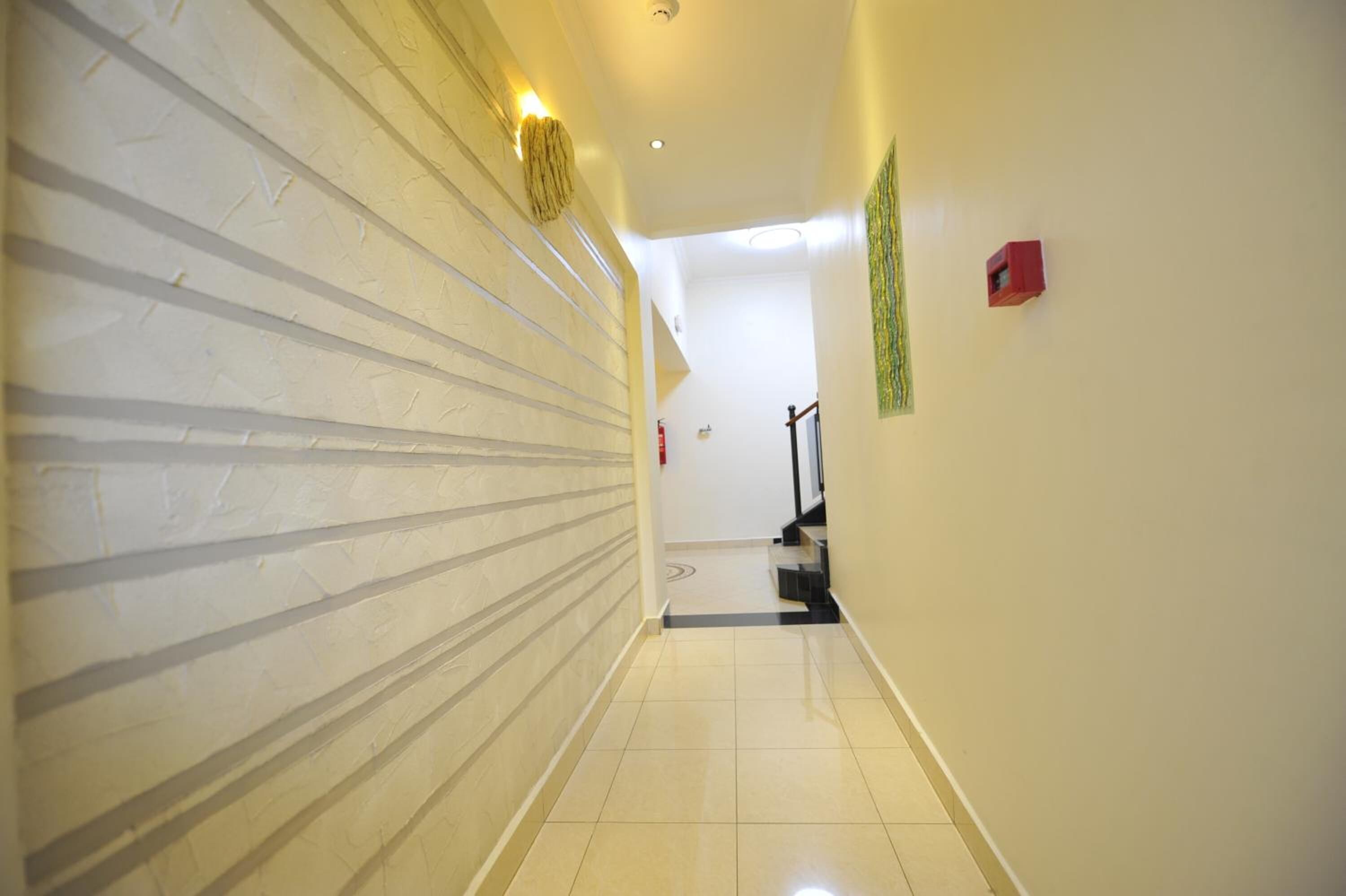 A hallway with a textured wall, a tiled floor, and a staircase at the end.