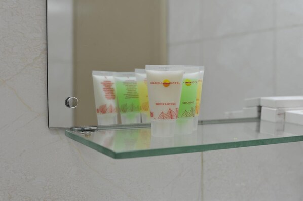Toiletries on a glass shelf in a bathroom.