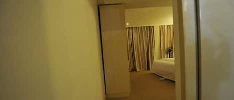 A hotel room with a bed, a nightstand, and a closed door.