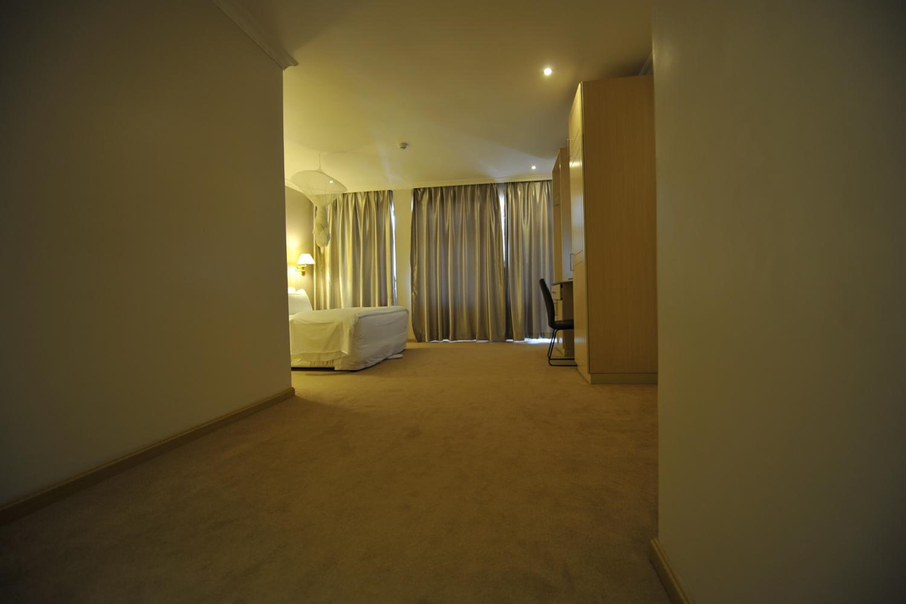 Een hotelkamer met een bed, bureau en gordijnen.