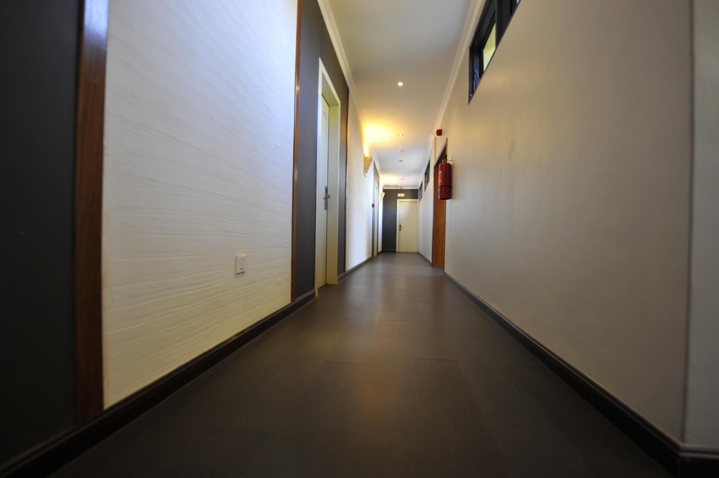 A long, narrow hallway with white walls and dark flooring.