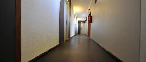 A long, narrow hallway with white walls and dark flooring.