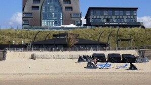 Een modern hotel met een unieke, gebogen gevel en een plat dak, met een zichtbaar telefoonnummer.