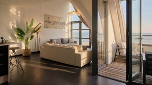 Een moderne woonkamer met een bank, een eethoek en uitzicht op zee.