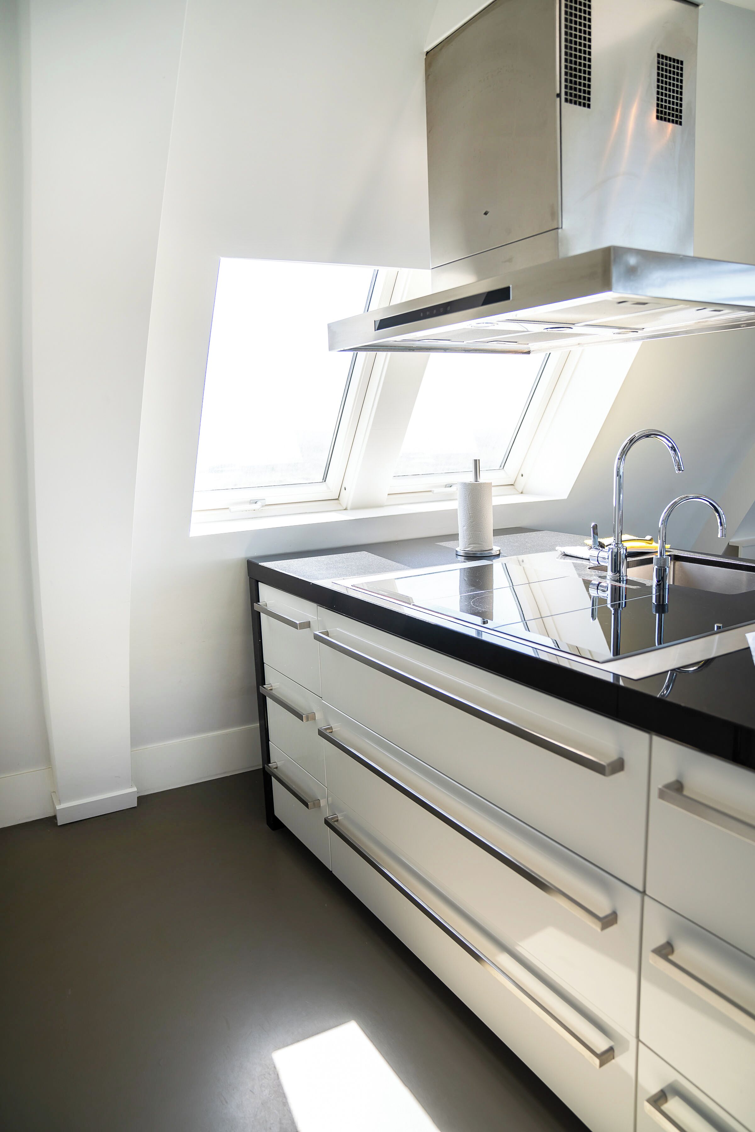 Una cocina moderna con tragaluz, electrodomésticos de acero inoxidable y encimera negra.