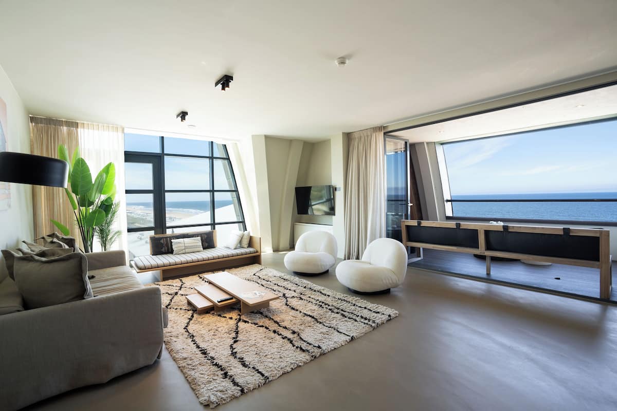 Una sala de estar moderna con un ventanal grande con vistas al mar, un sofá, una mesa de centro y un televisor.