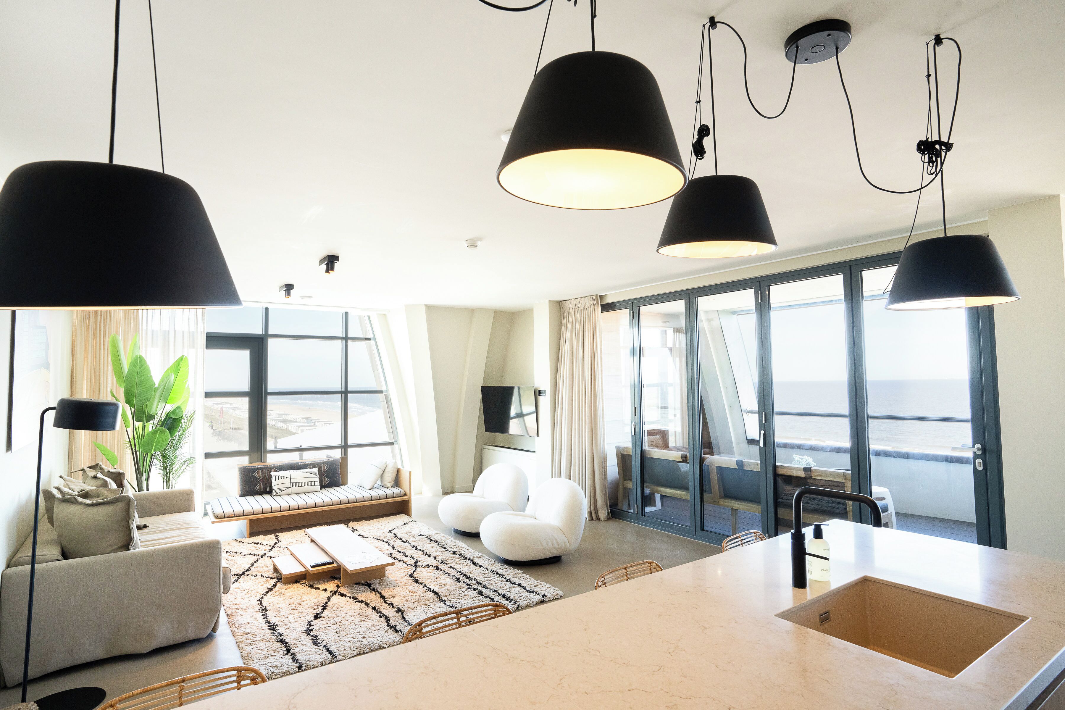 Un salon moderne avec un canapé, une table basse et une grande fenêtre donnant sur la mer.