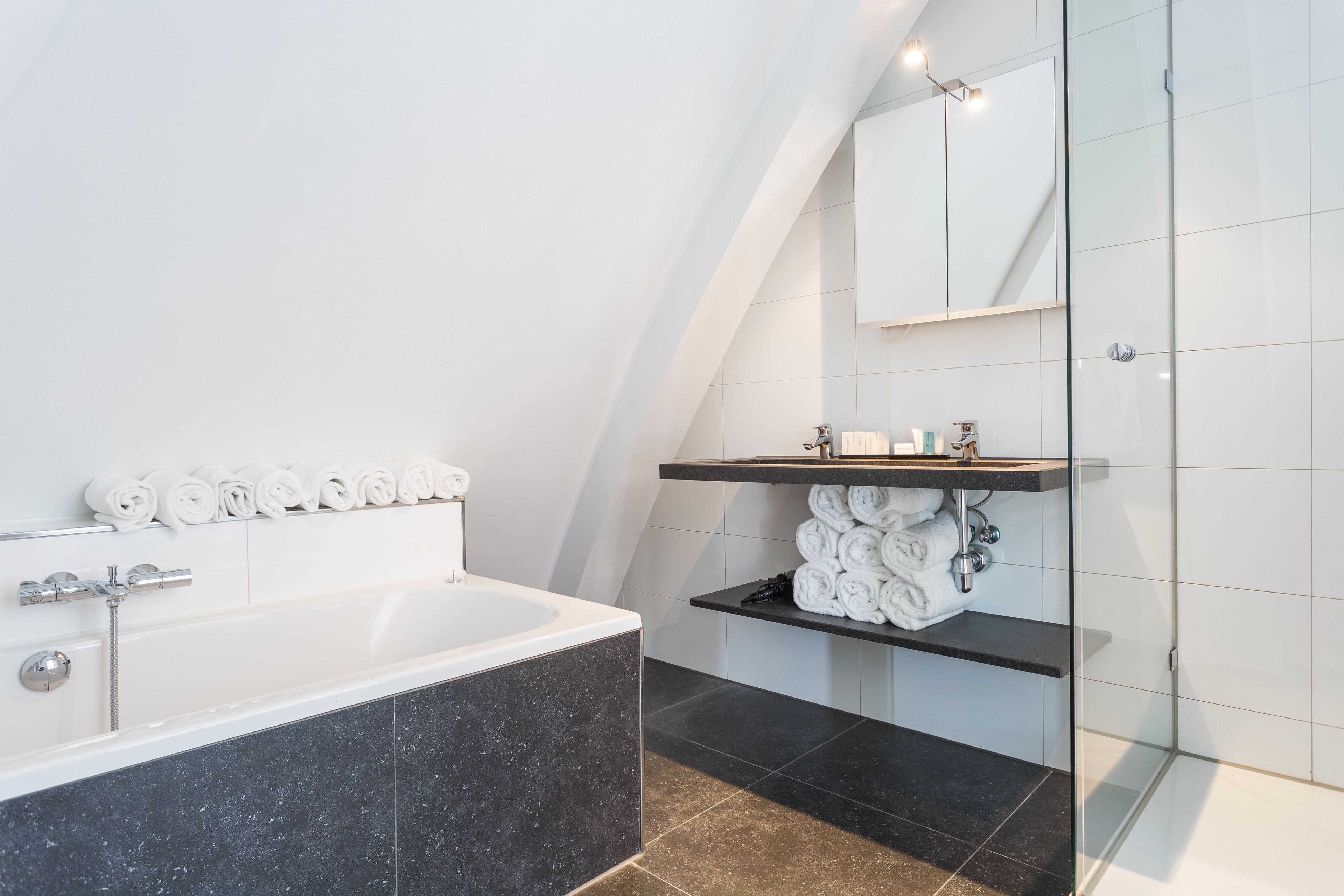 Ein modernes Badezimmer mit freistehender Badewanne, einer Duschkabine und einem Waschtisch mit Spiegel.