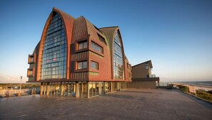 Stunning building with a curved design, featuring a glass and metal facade and a clear view of the surrounding landscape.