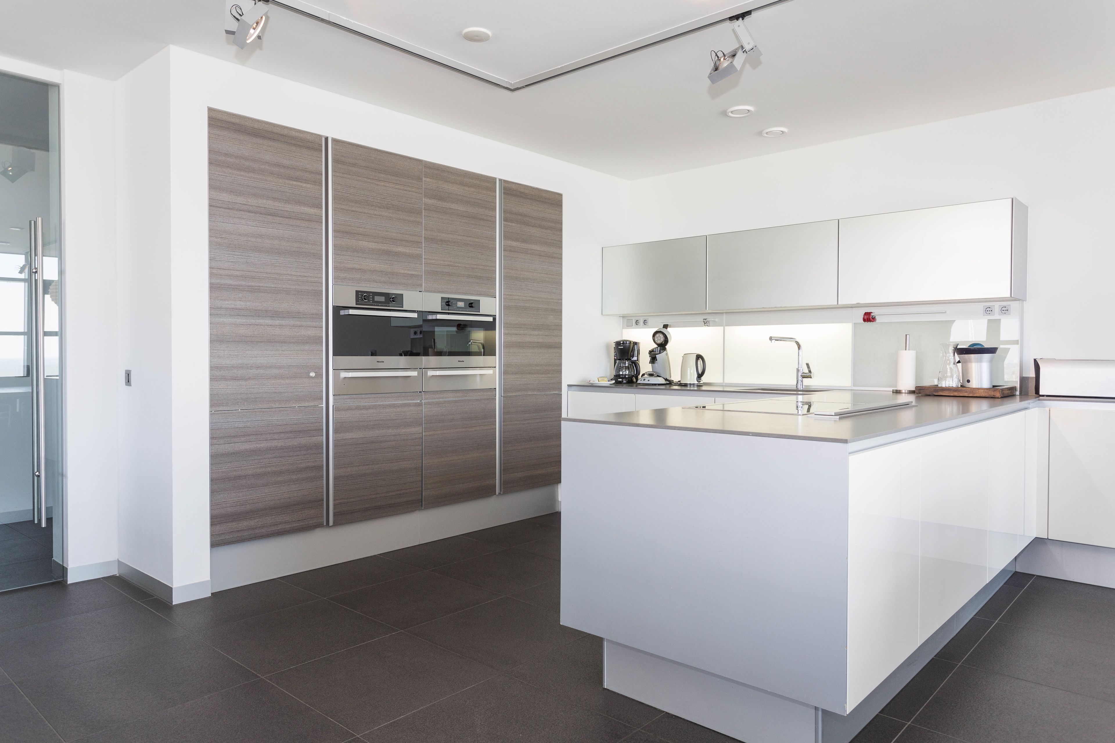 A modern kitchen with a central island, built-in appliances, and a large window.