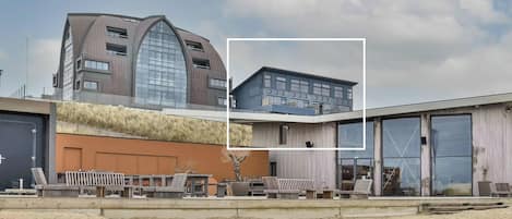 Ein modernes Gebäude mit einzigartiger, geschwungener Dachform, großen Fenstern und einem flachen Dachteil mit blauer Fassade.