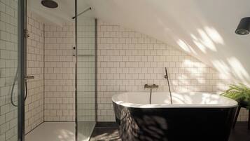 Un baño moderno con una bañera independiente, cabina de ducha con mampara de vidrio y una planta en maceta.