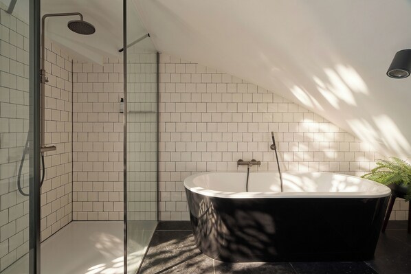 Une salle de bain moderne avec une baignoire sur pieds, une douche en verre et une plante en pot.