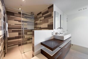 Enjoy a refreshing shower in this sleek bathroom with a glass-enclosed shower area and a spacious vanity.